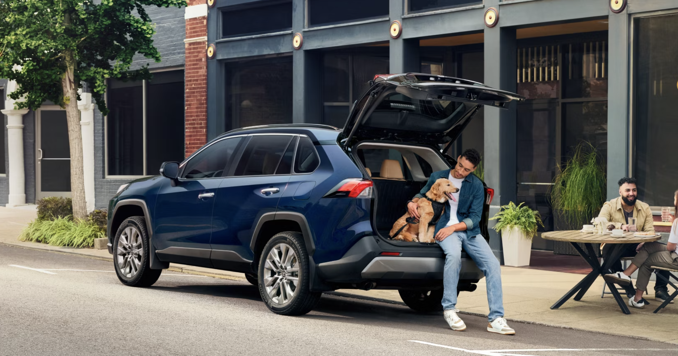 Man and his dog sitting in the trunk of a Used Toyota SUV from Oakbrook Toyota in Westmont